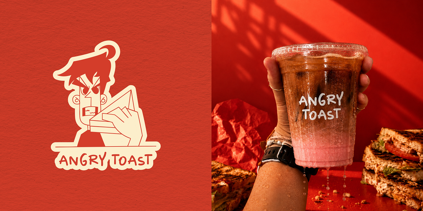 Angry Toast sticker mark beside an iced coffee held in front of a red wall