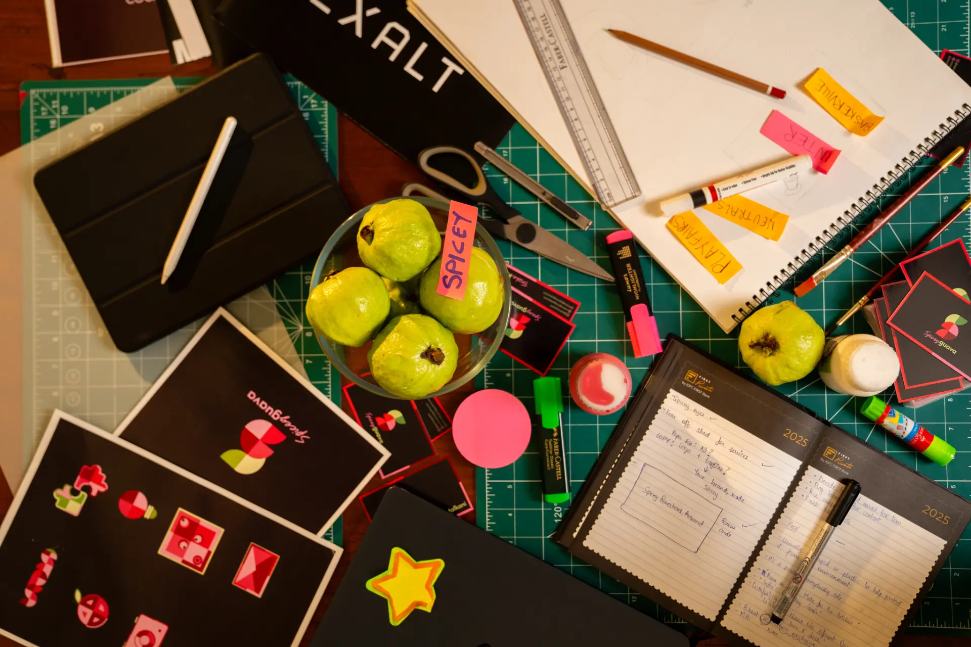 Spicey Guava brand materials, guavas and sketchbooks laid out on a cutting mat